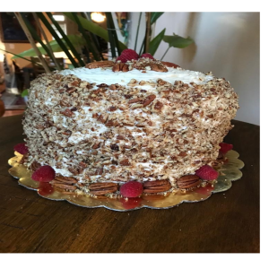 Moist southern red velvet cake with subtle cocoa and coffee flavor layered with rich cream cheese frosting topped with pecans soft bakery dessert cake